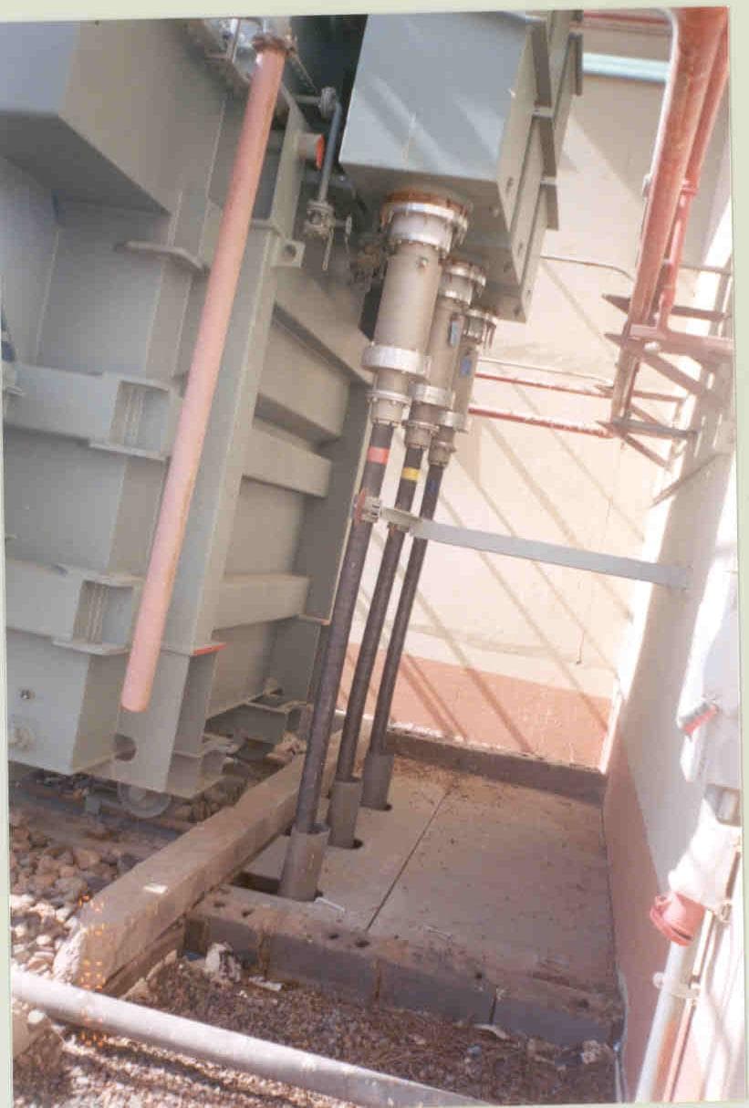 Precision high-voltage cable connection setup on a power transformer, featuring properly terminated cables and safety barriers.