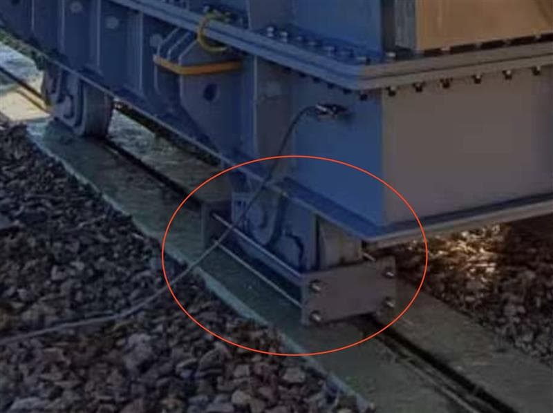 Close-up of the transformer wheel lock mechanism ensuring the unit remains stationary on its foundation rails.